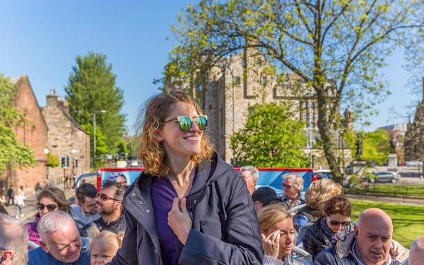 Tourists enjoying a sunny day on a Glasgow hop-on hop-off bus tour.