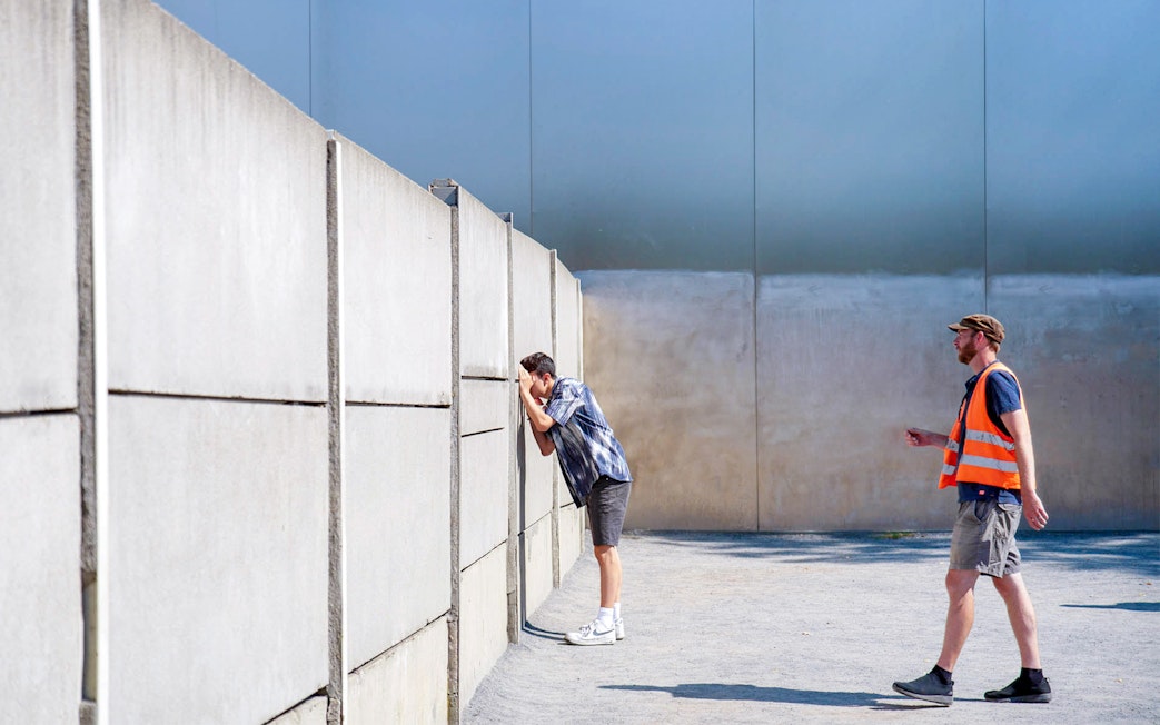 Man looking through Berlin Wall with guide during bike tour.