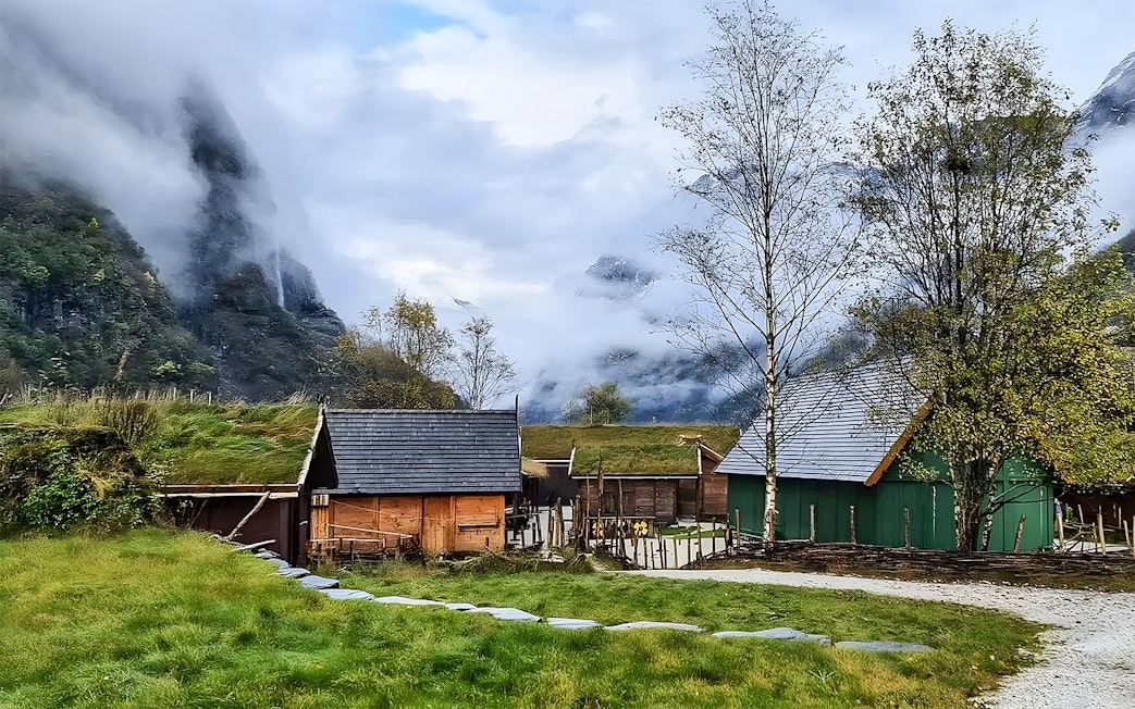 Viking village with grass-roofed houses in a misty valley near Bergen, Norway.