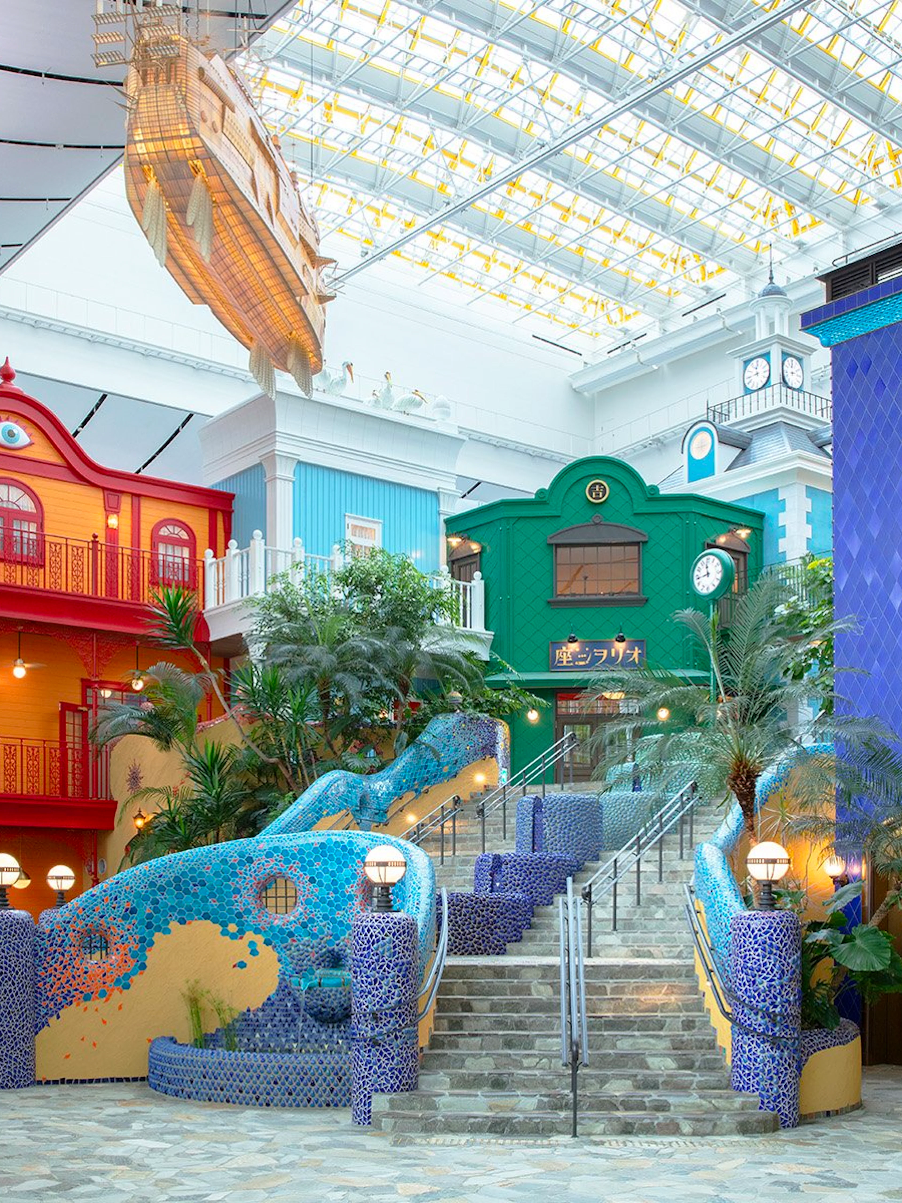 Ghibli's Grand Warehouse colorful buildings and staircase with lush greenery.
