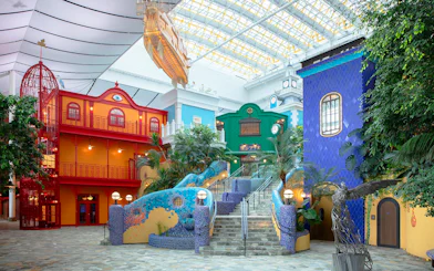 Ghibli's Grand Warehouse colorful buildings and staircase with lush greenery.