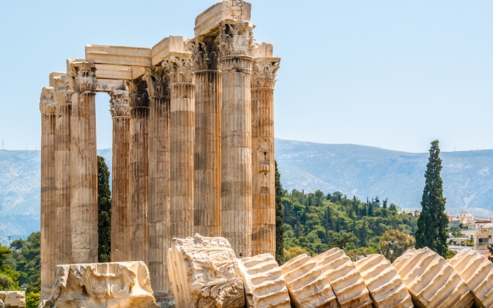 Ruins of the Temple of Olympian Zeus in Athens with mountains in the background.
