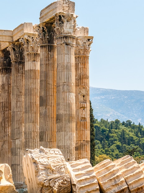 Ruins of the Temple of Olympian Zeus in Athens with mountains in the background.