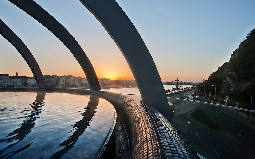 Rudas Thermal Spa pool overlooking Budapest skyline at sunset.
