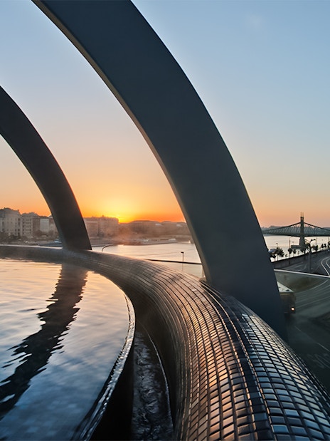 Rudas Thermal Spa pool overlooking Budapest skyline at sunset.