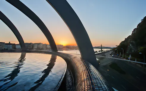 Rudas Thermal Spa pool overlooking Budapest skyline at sunset.
