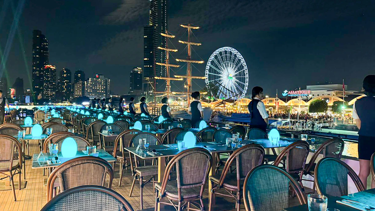 Staff preparing tables on Royal Princess cruise with Asiatique Ferris wheel in background.