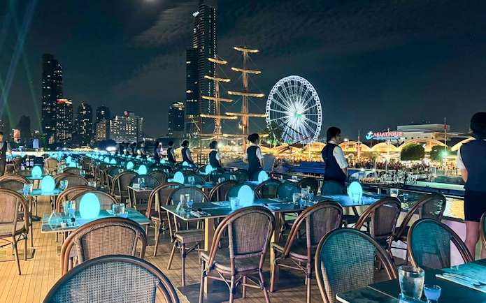 Staff preparing tables on Royal Princess cruise with Asiatique Ferris wheel in background.