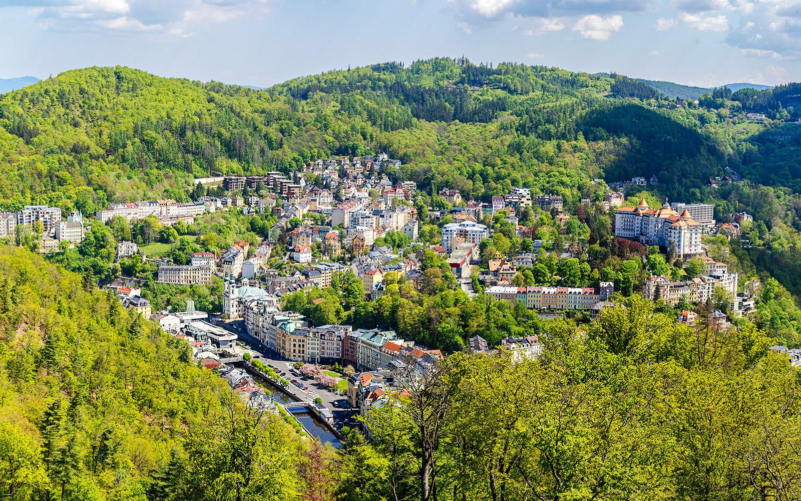 Panoramic view of Karlovy Vary with historic buildings and lush green hills.