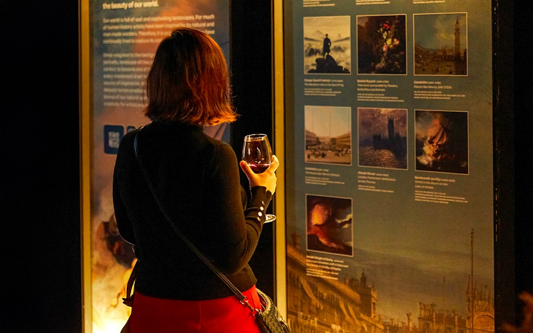 Visitor with drink exploring art exhibit at Frameless.