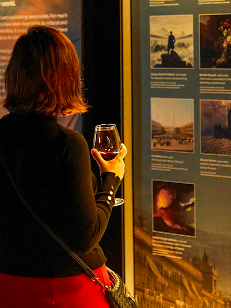 Visitor with drink exploring art exhibit at Frameless.