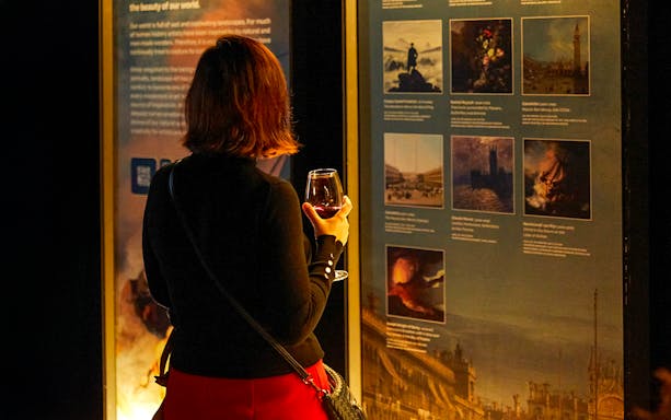 Visitor with drink exploring art exhibit at Frameless.