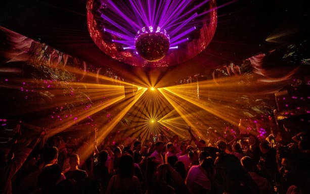 DJ performing under vibrant lights at La Troya Club Chinois, Ibiza.
