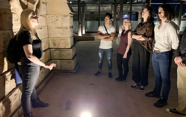 Tour guide narrating Brisbane's true crime stories to a group at night.