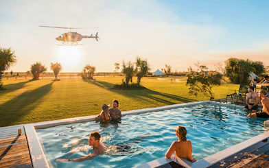 Helicopter flying over guests in a pool at Top End Safari Camp, Finniss River.