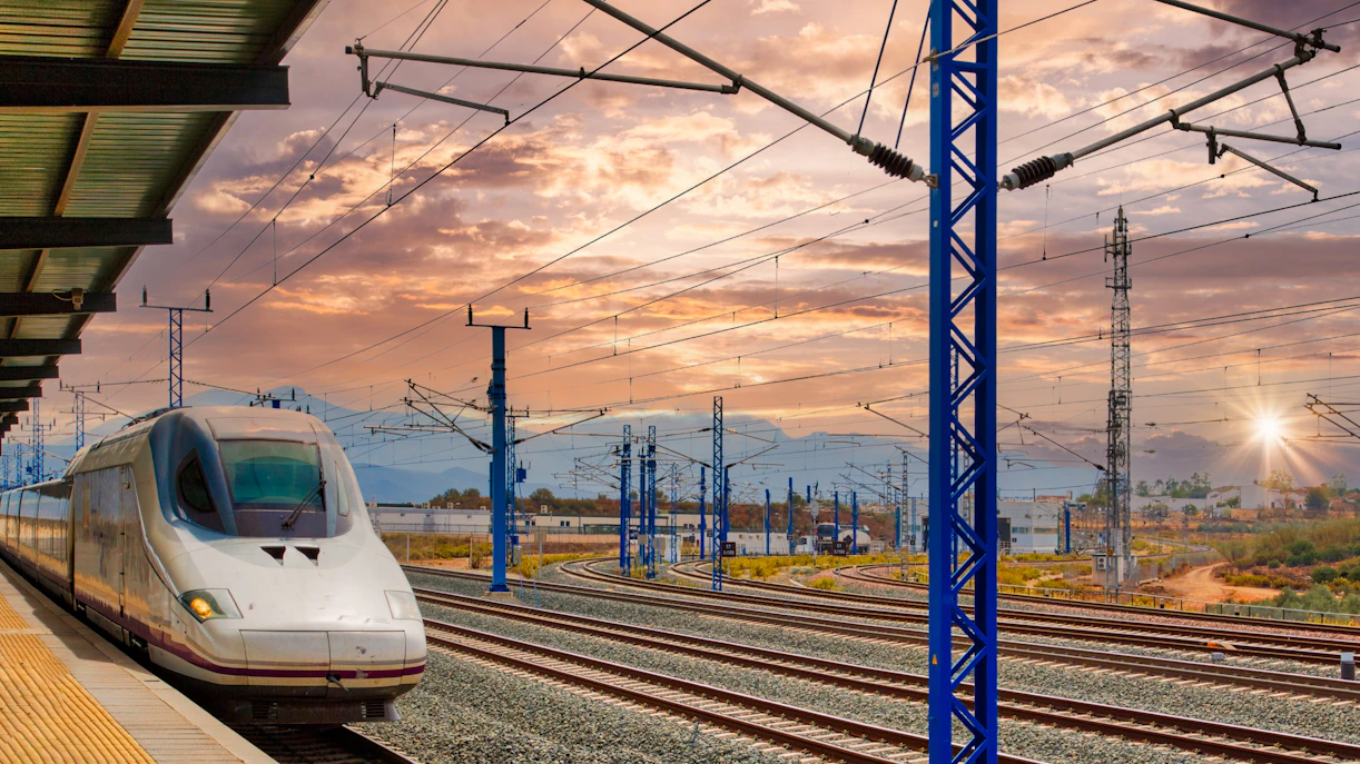 High-speed train at a station in Seville, Spain during sunset.