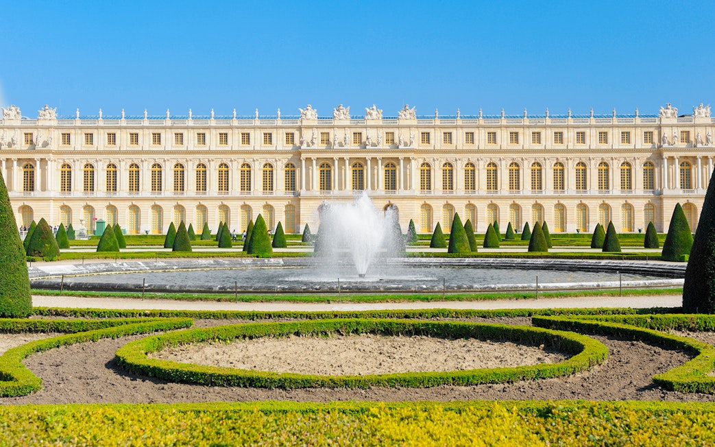 Palace of Versailles front view with fountain and gardens in France.