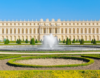 Palace of Versailles front view with fountain and gardens in France.