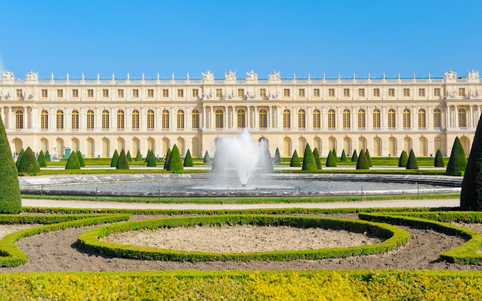 Palace of Versailles front view with fountain and gardens in France.