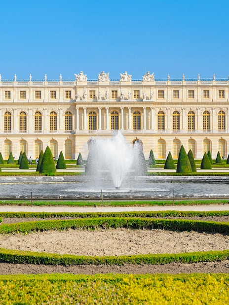 Palace of Versailles front view with fountain and gardens in France.