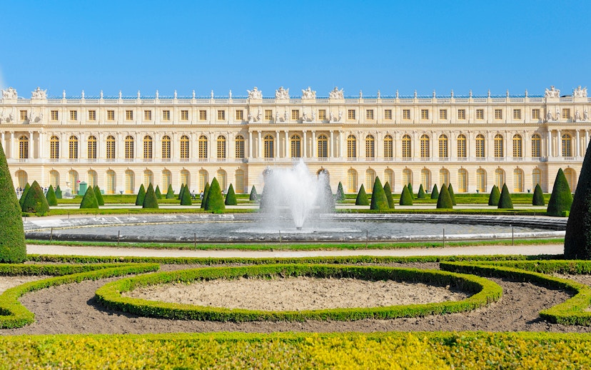 Palace of Versailles front view with fountain and gardens in France.