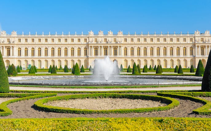 Palace of Versailles front view with fountain and gardens in France.