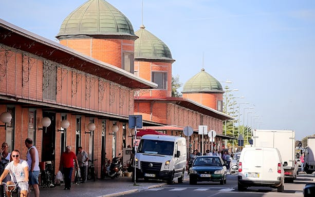 Street view of the Olhão Market in Eastern Algarve with people and vehicles.