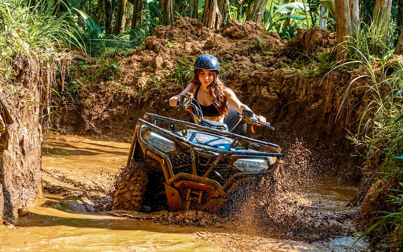 ATV rider navigating muddy terrain in Ubud jungle.