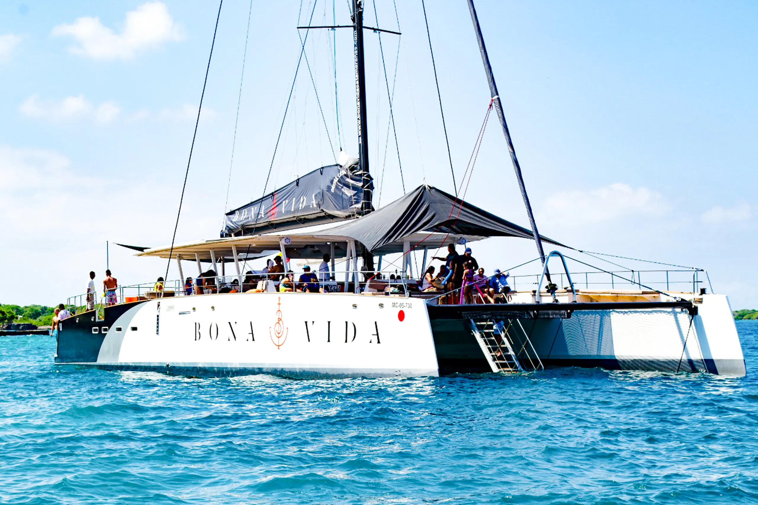 Catamaran with passengers on a sunset open bar tour in Cartagena, sailing on blue waters.
