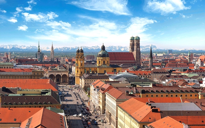 Munich cityscape with Frauenkirche and Theatine Church under blue sky.
