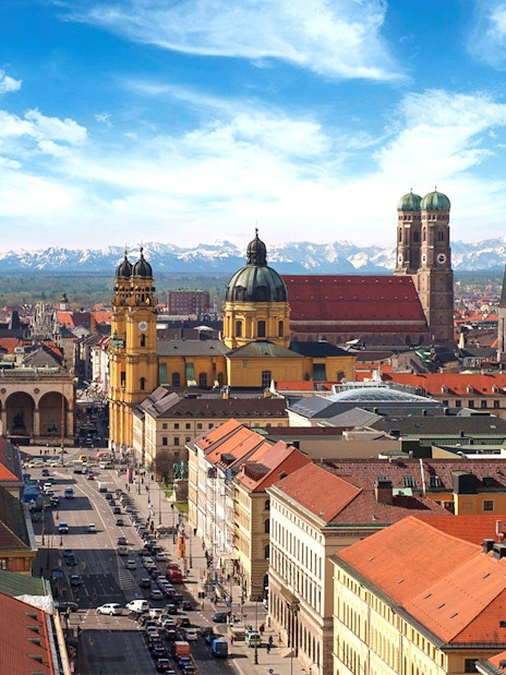Munich cityscape with Frauenkirche and Theatine Church under blue sky.