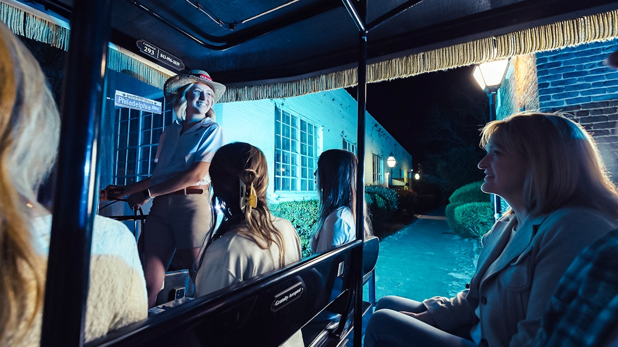Carriage tour guide leading a group through Charleston's historic streets at night.