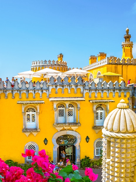 Pena Palace in Sintra, Portugal, with vibrant yellow facade and tourists exploring.