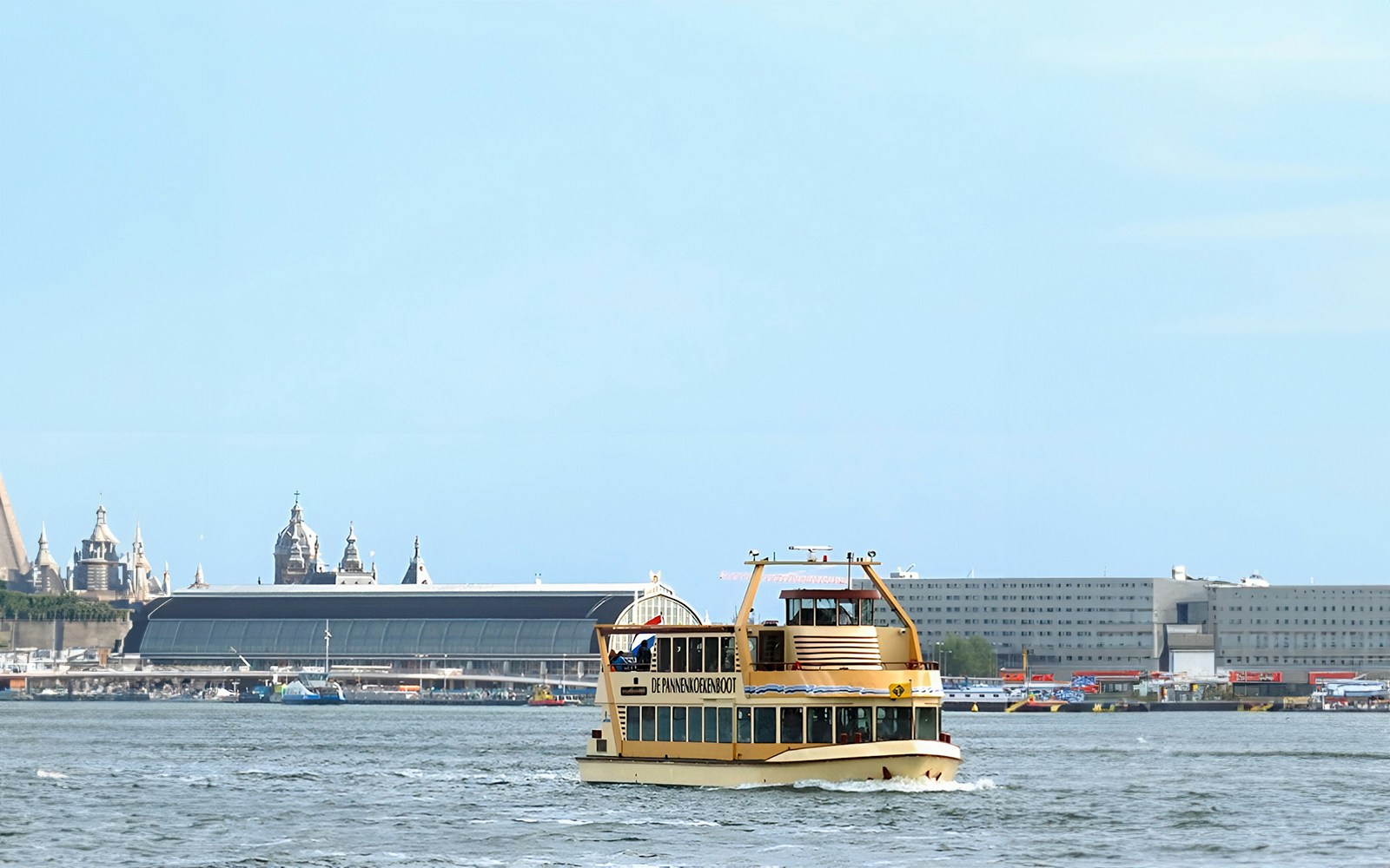 Tourists enjoying a Pancake Cruise in Amsterdam, sailing on a canal with city view