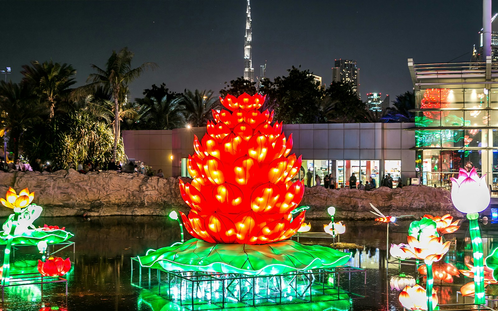 Illuminated giant flower display at Dubai Garden Glow with Burj Khalifa in the background.