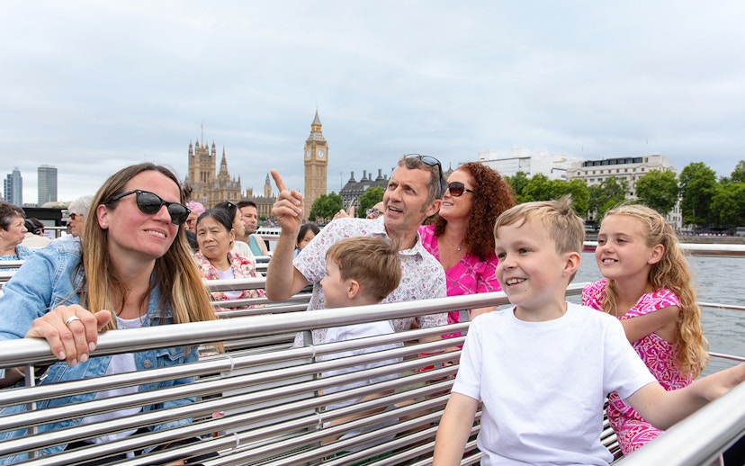 Family enjoying Thames river cruise with view of Big Ben, London.