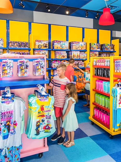 Family shopping at LEGOLAND California store with LEGO merchandise displays.