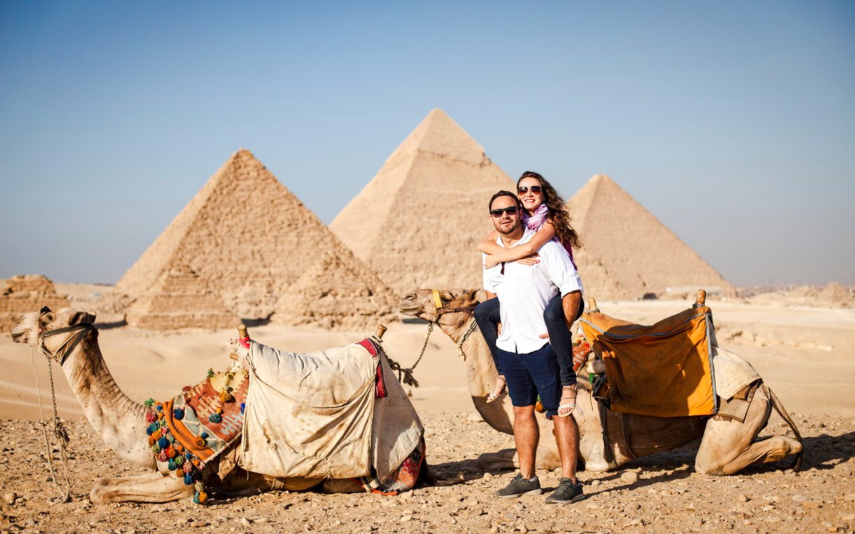 Couple with camels in front of the Pyramids at Giza Complex, Egypt.