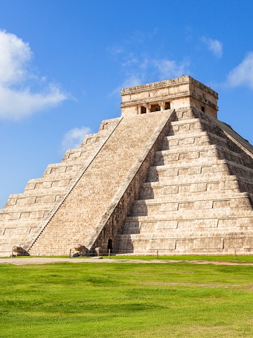 Chichén Itzá pyramid with tourists exploring the ancient Mayan site in Cancún, Mexico.