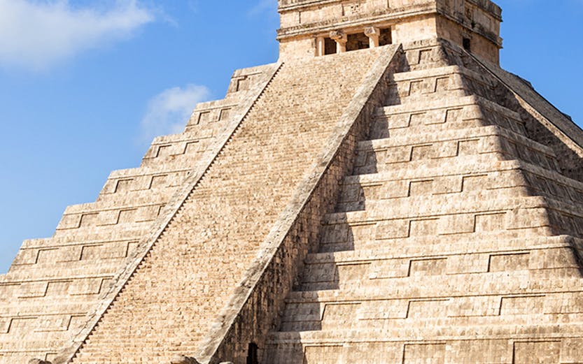 Chichén Itzá pyramid with tourists exploring the ancient Mayan site in Cancún, Mexico.