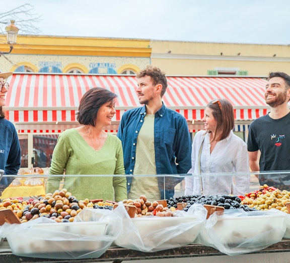 Tour group exploring a market in Nice with local guide.