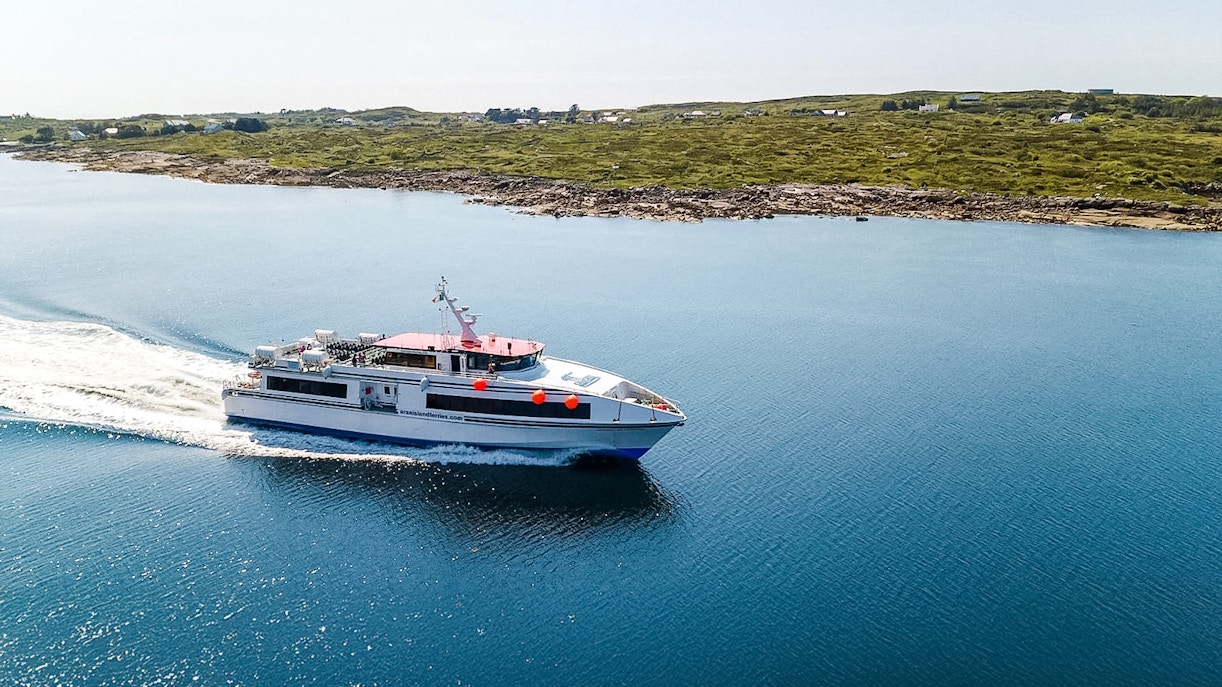 Ferry cruising near the Aran Islands with coastal landscape in the background.