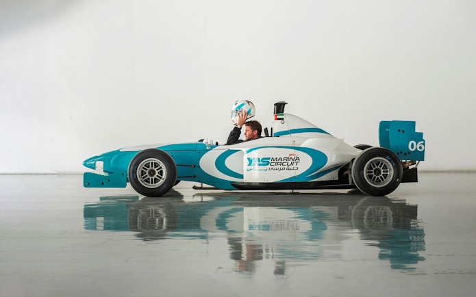 Driver holding helmet in Yas Marina Circuit race car for FORMULA YAS 3000 Driving Experience.