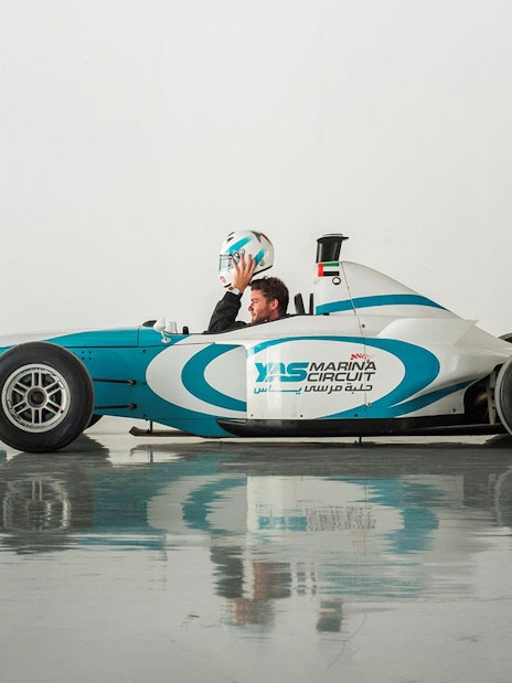Driver holding helmet in Yas Marina Circuit race car for FORMULA YAS 3000 Driving Experience.