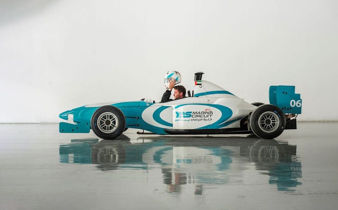 Driver holding helmet in Yas Marina Circuit race car for FORMULA YAS 3000 Driving Experience.