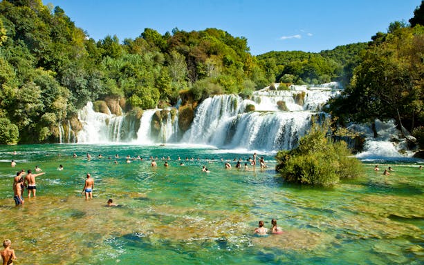 Visitors swimming in Krka National Park waterfalls, Croatia.
