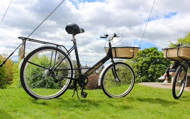 Bicycle with basket used for Glasgow Highlights Bike Tour on grassy hill.