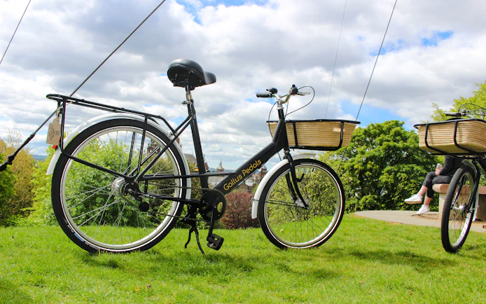 Bicycle with basket used for Glasgow Highlights Bike Tour on grassy hill.