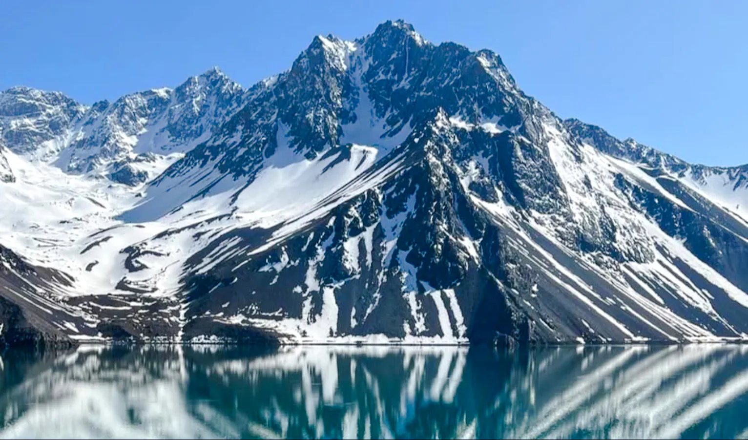 Snow-capped Andes mountains reflecting in Embalse del Yeso, Cajón del Maipo, Santiago.
