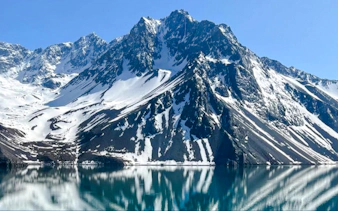 Snow-capped Andes mountains reflecting in Embalse del Yeso, Cajón del Maipo, Santiago.
